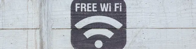 Un pochoir noir « FREE Wi Fi » avec le symbole des ondes sans fil peint sur un mur en béton texturé.