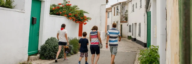 Famille marchant dans une rue avec l’église des Portes-en-Ré.