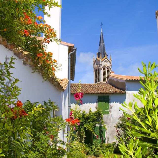 Clocher de l'église de La Couarde vu depuis une ruelle fleurie