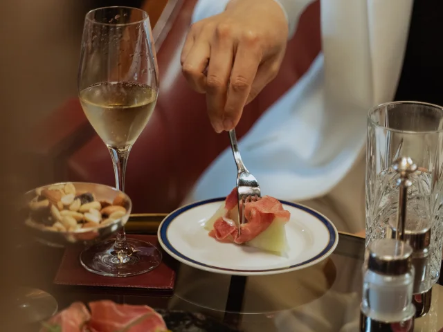 Personne prenant une bouchée d’un amuse-bouche accompagné d’une coupe de champagne.