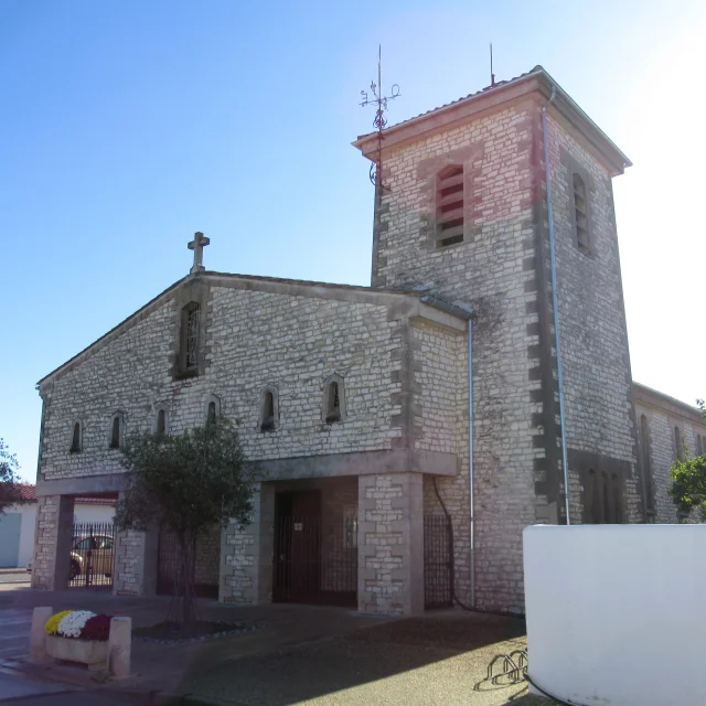 Façade de l'église en pierres apparentes de Rivedoux prise en contre plongée avec son clocher massif sur la droite