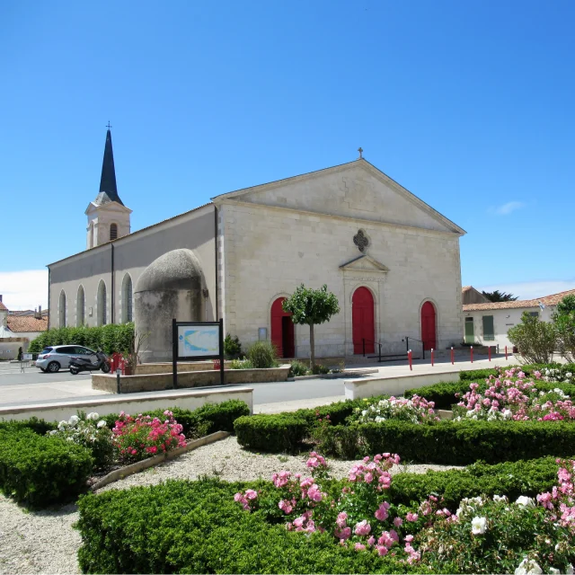 Église de Saint-Clémen avec son clocher en fond et un jardin fleuri au premier plan