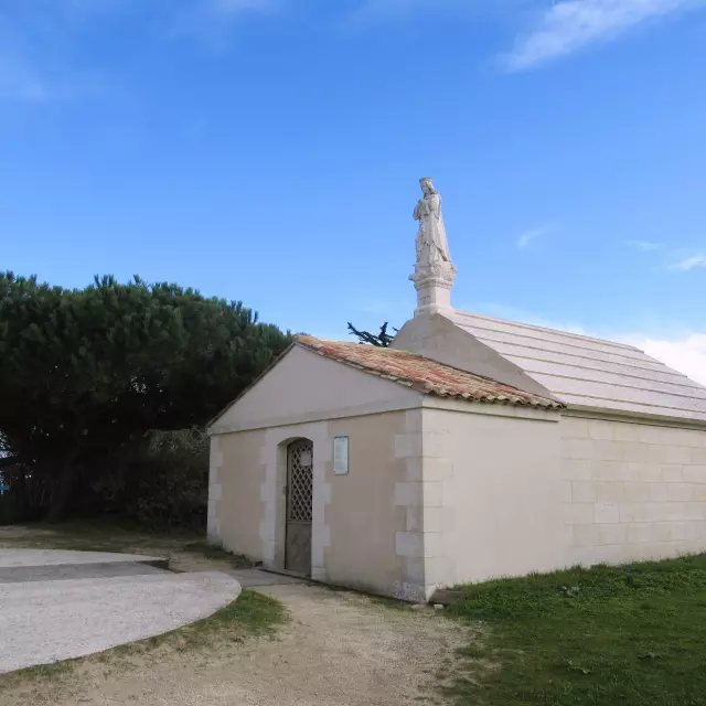 Petite chapelle surmontée d'une statue de la Vierge face à une placette