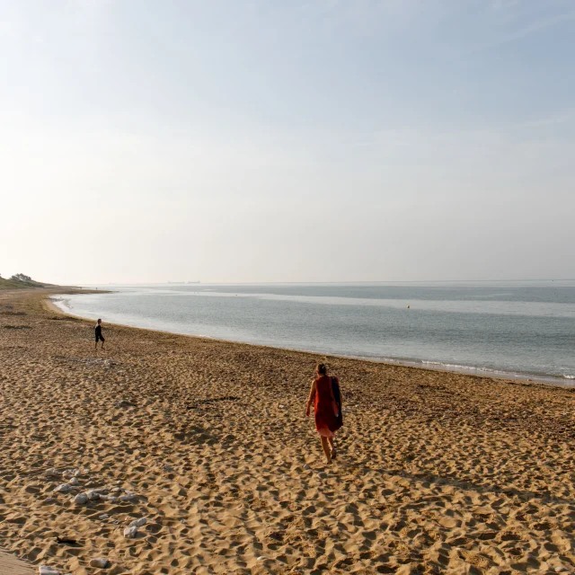 Personnes se promenant sur une plage de sable à Sainte-Marie face à la mer à leur droite