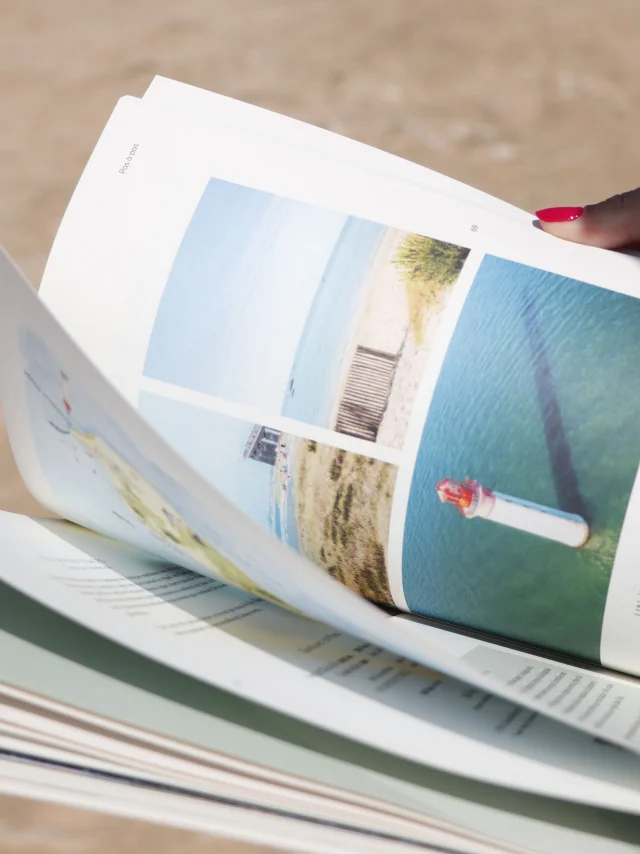 Une personne feuilletant le magazine Instants sur une plage.