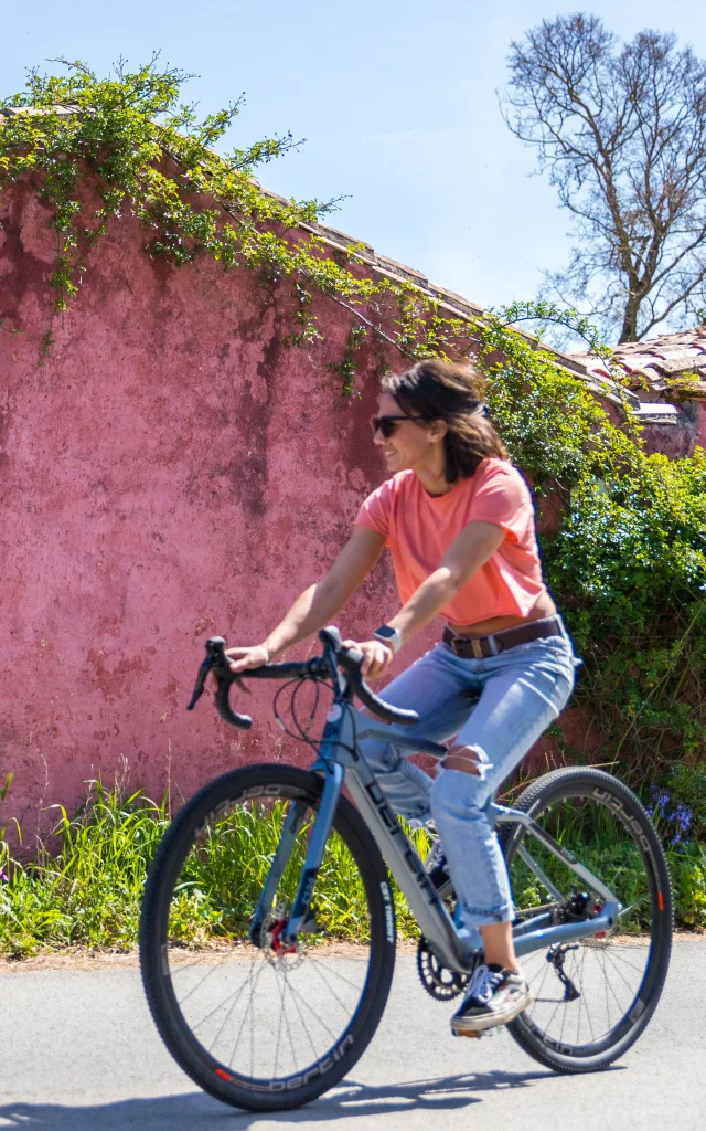 Femme à vélo passant devant la maison rose des Portes-en-Ré.