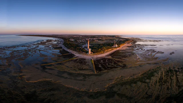 Vue aérienne du phare des Baleines sur la côte avec des marais au coucher du soleil.
