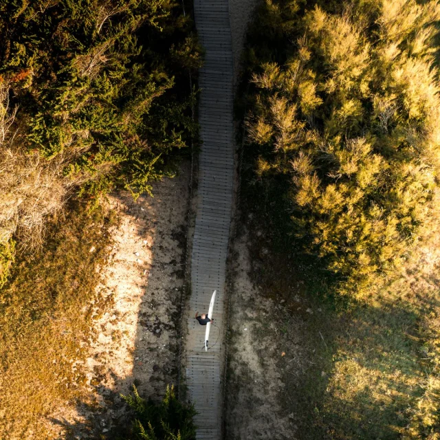 Vue aérienne d'un chemin dans les dunes avec un surfeur
