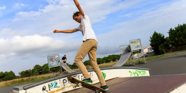 Un adolescent effectuant une figure en skateboard dans un skatepark.