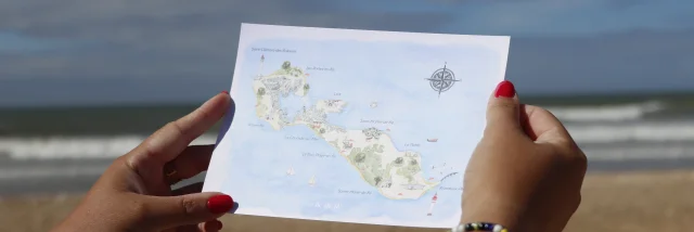 Personne tenant une carte postale de l'île de Ré avec la mer en arrière-plan.