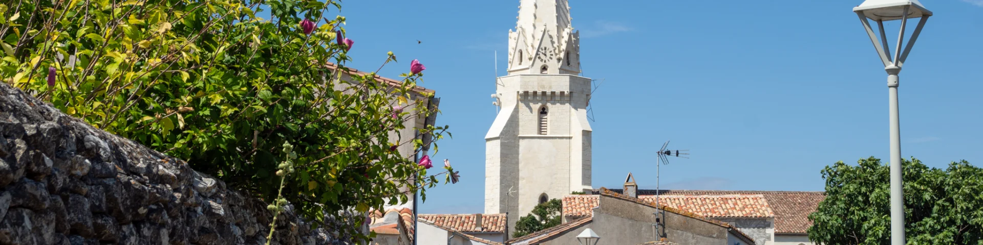 Église de Sainte-Marie vue depuis une ruelle bordée de murs en pierre.