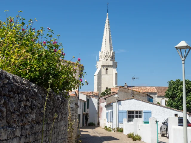 Église de Sainte-Marie vue depuis une ruelle bordée de murs en pierre.