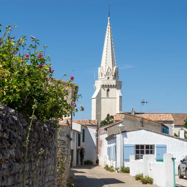 Église de Sainte-Marie vue depuis une ruelle bordée de murs en pierre.