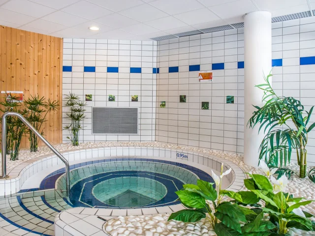 Espace bien-être du centre aquatique avec bain à remous et décoration végétale