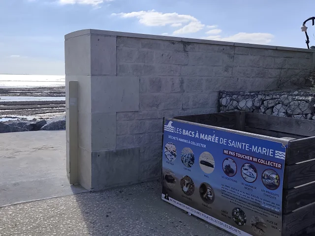 Bac à marée bleu posé contre un muret près du littoral