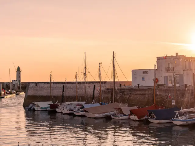 Des voiliers sont amarrés dans le port de La Flotte au coucher du soleil.