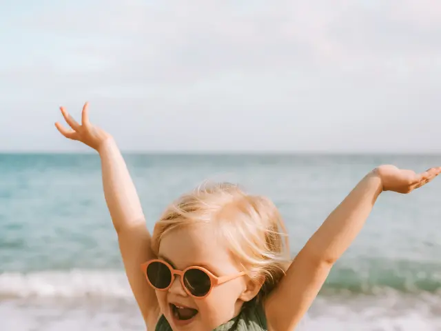 Feliz niña jugando en la playa emocional niño en gafas de sol 3 años de edad niño levantó las manos familia viajes estilo de vida vacaciones al aire libre