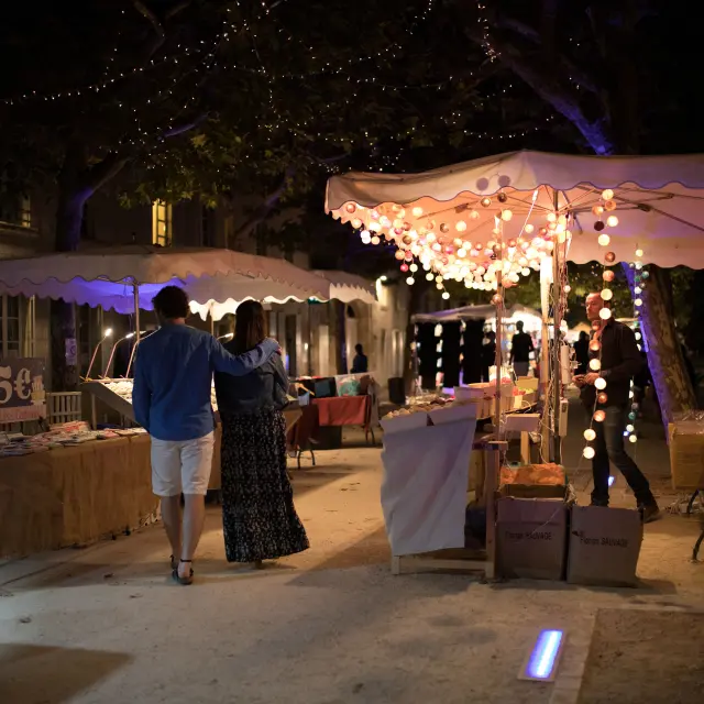 Night market alley decorated with fairy lights and lined with stalls.